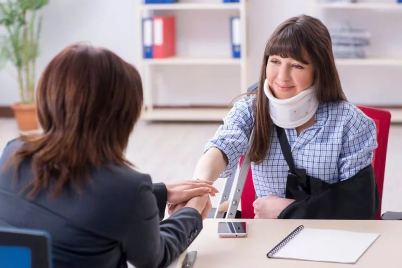 injured woman with neck brace talking to pi lawyer