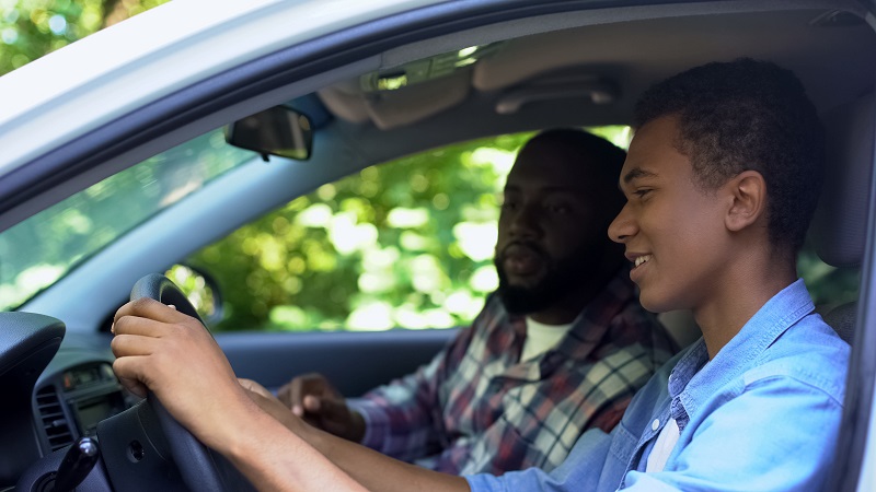 Parent teaching son driving strategies to avoid car accidents in Houston
