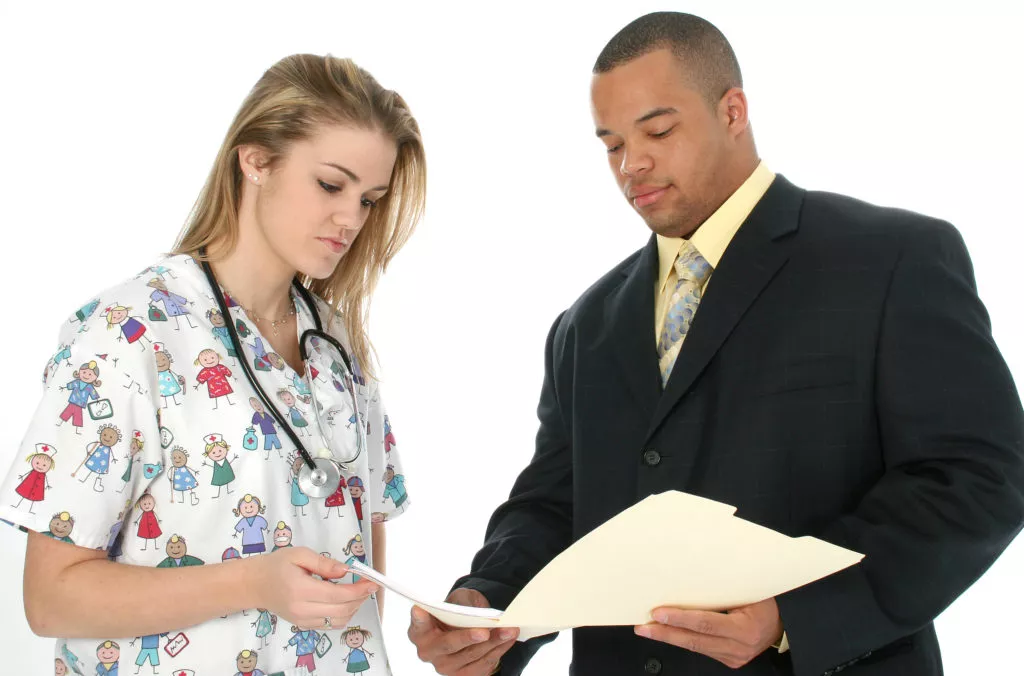 Doctor and lawyer reviewing pre-existing medical conditions documents after a car accident.